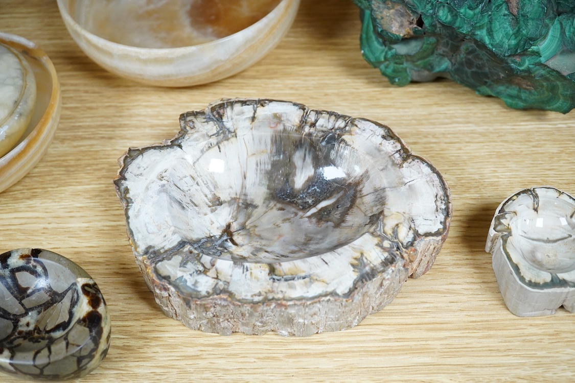 Two petrified wood ashtrays, a malachite rock, three onyx bowls, one with cover, and one other item, larger ashtray 17.5cm wide